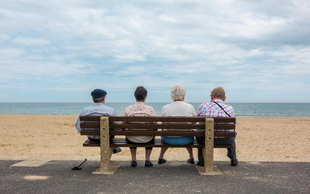 Four people on a bench at the beach