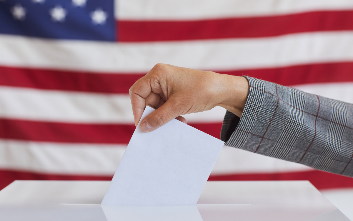 hand placing envelope in a ballot box
